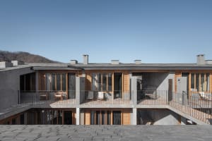 A modern residential building with concrete and wooden exterior.