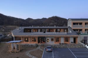 A hotel with a wooden exterior and stone walls at night, surrounded by mountains.