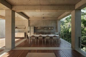 Modern dining room with concrete exterior and steel and wooden furniture.