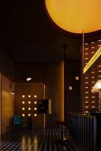 Modern industrial-style hotel reception area with concrete walls and floor tiles.