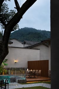Outdoor space featuring a wooden terrace with seating and a poolside area.