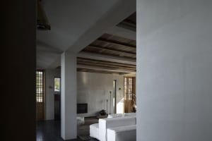 A minimalist living room with concrete walls and a wooden ceiling.