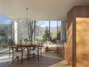 A minimalist residential kitchen featuring wood elements and a view of the mountains through floor-to-ceiling windows.