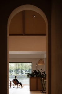 A spacious coffee shop with a modern, minimalist design featuring natural wood and woven textures.