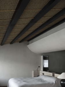 Interior of a modern minimalist bedroom featuring a concrete finish and a view of the ocean through a window.