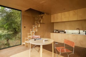 Minimalist kitchen with a natural wood finish, featuring a round table and chairs, a kitchen counter with cabinets, and a lad