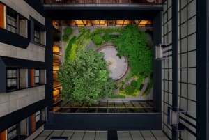 A modern, circular green courtyard made of concrete and surrounded by greenery, viewed from above.