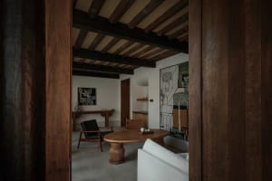 A modern living room with wooden furniture, leather accents, and concrete flooring.