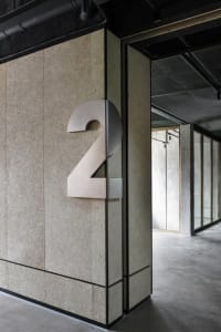 A modern building number sign made of metal attached to a wall.