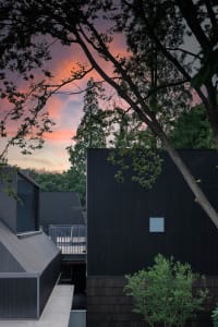 Modern exterior featuring sleek, black metal-clad panels under a dramatic, sunset sky.