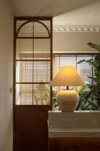 A ceramic lamp with a conical shade illuminates a space, adding a warm glow.