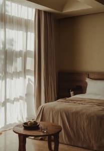 Modern bedroom with textured fabric, minimalistic style, large window, natural light, and wooden furniture.