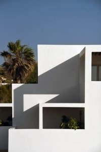 A modern building facade with white walls and green plants.