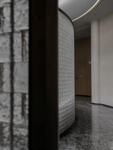Modern interior hallway with granite columns and a curved wall.