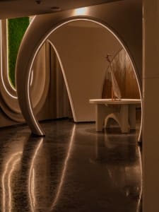 A modern lobby with curved concrete arches and neon lights.