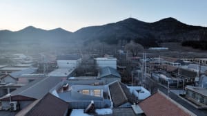 Aerial view of rooftops and mountains in an urban setting.