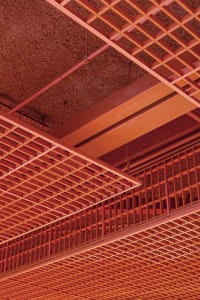 A close-up view of an industrial building interior featuring a steel grid structure and a textured, rusted ceiling.