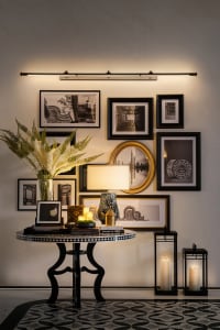 Modern living room with decorative objects in black, white, and gold colors, featuring a patterned floor and a wall collage o
