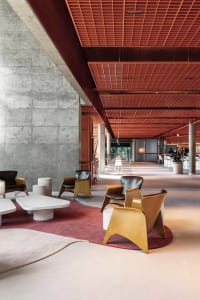 Modern lobby featuring concrete walls, wooden furniture, and a red-wood ceiling.