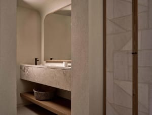 A modern minimalist bathroom featuring a marble sink with a wooden shelf underneath and a large mirror above.