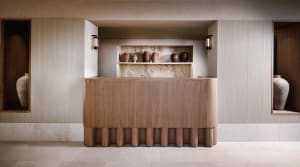 Modern reception desk with wooden panels and built-in shelves displaying ceramic vases.