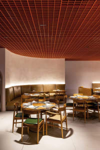 Modern restaurant interior with wooden tables, chairs, and leather seating.