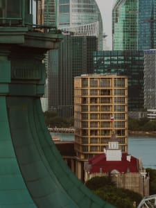 A modern architectural building with glass windows, surrounded by other tall skyscrapers.