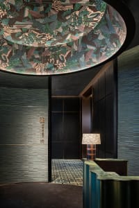 A contemporary lobby with a visually striking ceiling design, featuring a mix of materials and dark wood finishes.