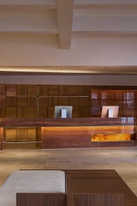 A modern hotel lobby with a wooden reception desk and marble accents.