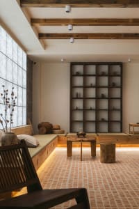 A modern living room with a wooden floor, low wooden furniture, and a large window.