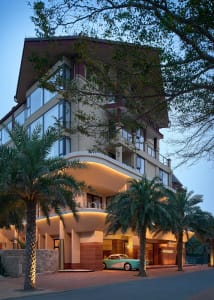 Modern hotel exterior featuring concrete, glass, and palm trees.