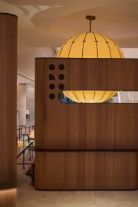 A modern restaurant bar with a wooden counter featuring integrated circular yellow lights.