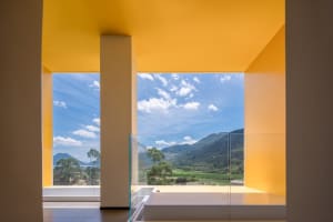 Modern window overlooking lush mountains and clear blue sky