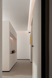 A minimalist white interior with clean lines and a modern design aesthetic, featuring a hallway with a sleek white floor and 