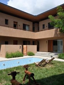 Modern concrete pool house with glass doors and pool in the yard.