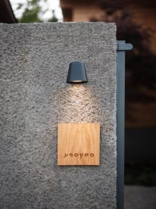 A modern wall-mounted light fixture attached to a textured concrete wall.