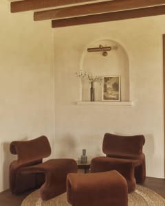 A modern living room featuring comfortable brown velvet couches, a wooden floor, and a warm, inviting ambiance.