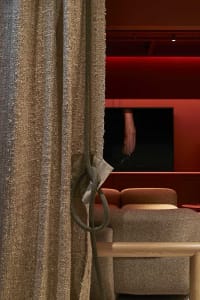 A textured fabric curtain with a rope tieback in a cozy residential living room setting.