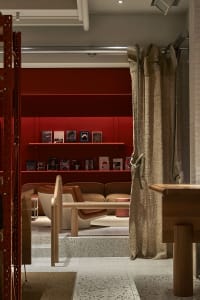A modern coffee shop featuring red walls, white wooden tables, and a cement floor.