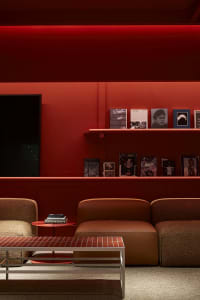 Modern living room with concrete walls and floor, leather sofa, and fabric seating
