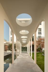 A modern residential corridor featuring concrete flooring and glass roof sections.