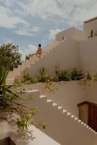 A person walking up a modern, concrete staircase with plants on the walls.