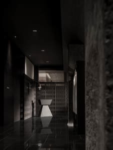 A dark, industrial-style corridor with concrete walls and a geometrically shaped table in the center.