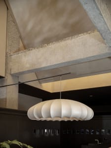 A modern, sleek chandelier hangs from the ceiling in a contemporary living room.