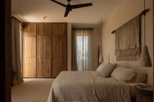 A minimalist bedroom features wooden cabinets and neutral textiles, creating a serene and functional space.