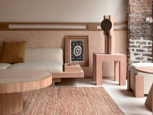 A minimalist living room featuring wooden furniture and a brick wall.