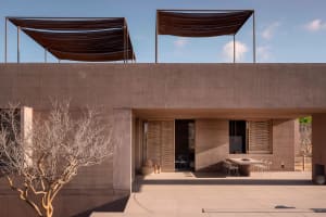 Concrete patio with modern design features, including a covered seating area and natural tree.