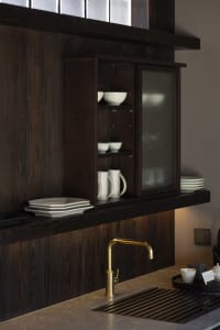 A modern minimalist kitchen with a wooden cabinet and white dishes.