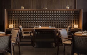 Modern restaurant interior with wooden furniture and lattice partitioning.