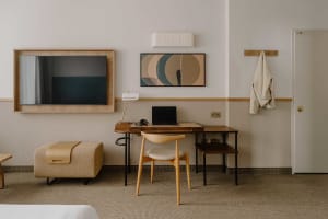 Modern, minimalist residential interior with wooden desk, digital tablet, and abstract art on the wall.